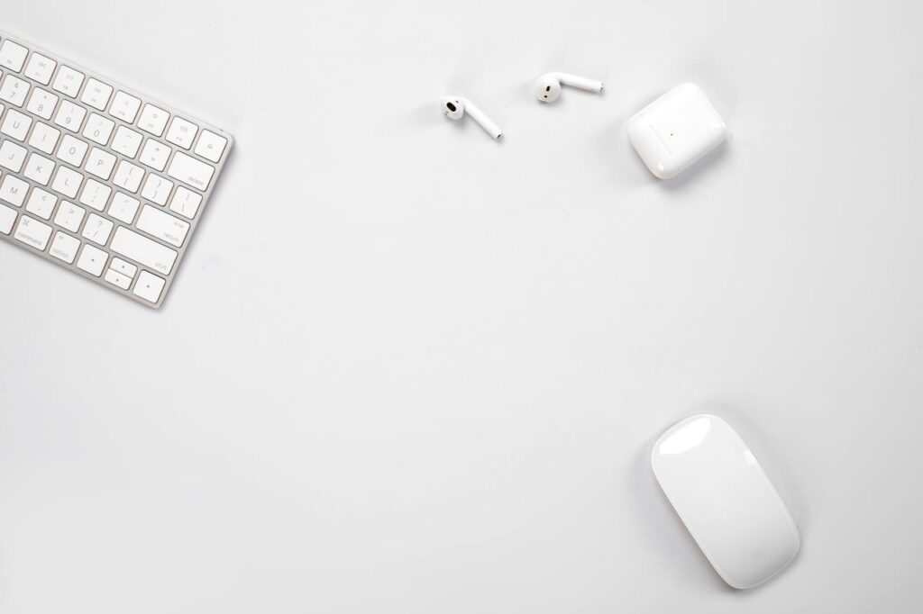 An overhead view of a sleek ergonomic mouse and matching mechanical keyboard neatly arranged on a modern minimalist wooden desk under soft lighting.